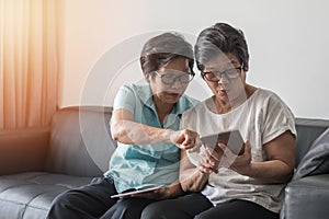 Ageing society concept, Asian elderly senior adult women sisters using mobile digital tablet smart phone application for social