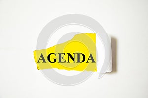 Agenda the text is written on a white background and a yellow piece of paper