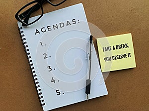 Agendas text on a note pad with pen, sticky note and glasses background. photo