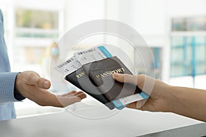 Agent giving passports and tickets to man at check-in desk in airport, closeup