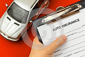 Agent hold Auto and car insurance form in hand. Clipboard with official agreement and policy document. Background with