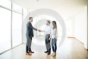 Agent Shaking Hands With Man By Woman In New Home