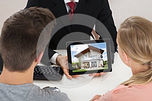 Agent Showing House On Digital Tablet To Couple