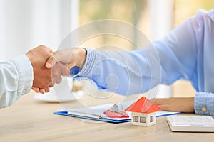 Agents and clients shake hands after signing paperwork and making a business agreement to transfer property rights. Concept of