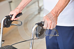 Ages senior man using walker indoor, detail on man's hands