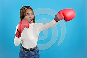 Aggressive african woman wearing boxing gloves throwing a punch