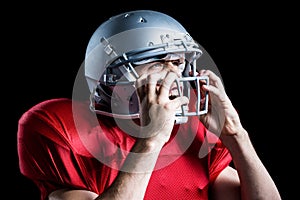 Aggressive American football player holding helmet