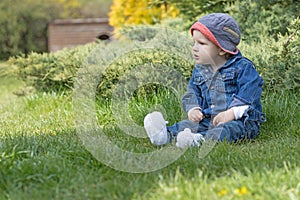 Aggressive angry baby boy is sitting on the grass