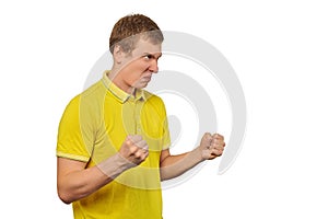 Aggressive angry man in yellow T-shirt ready to fight with fists isolated on white background
