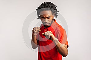 Aggressive bearded man with dreadlocks wearing red casual style T-shirt, holding clenched fists up