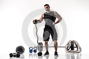 Aggressive bearded strong muscular Man in sportswear with barbell and sport equipment on white isolate
