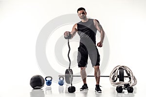 Aggressive bearded strong muscular Man in sportswear with barbell and sport equipment on white isolate