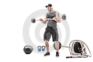 Aggressive bearded strong muscular Man in sportswear and headphones workout with barbell on white isolate