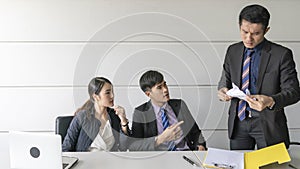 Aggressive boss businessman holding paper file work and complain staff and colleague in meeting conference room