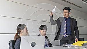 Aggressive boss businessman holding paper file work and complain staff and colleague in meeting conference room