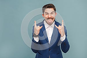 Aggressive businessman tongue out and showing rock and roll sign