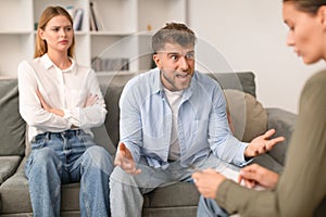 Aggressive husband shouts in anger during tense therapy session indoor