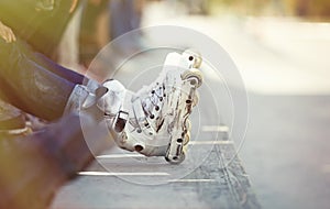 Aggressive inline rollerblader sitting in outdoor skate park