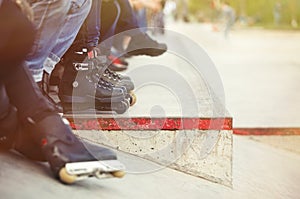 Aggressive inline rollerblader sitting in outdoor skate park