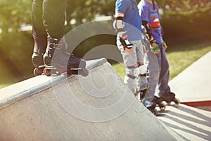 Aggressive inline rollerblader standing on ramp in skatepark