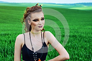 Aggressive makeup girl, amazon character in a green wheat field