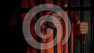 Aggressive male prisoner holding bars with injured hands, violence in jail