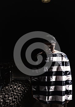 Aggressive male prisoner standing near his bed in a small dark p