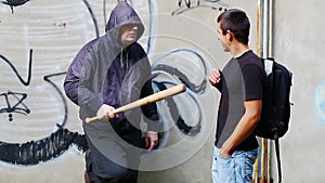 Aggressive man with a baseball bat talking with teenager