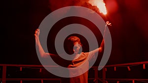 Aggressive man burning signal flare on roof. Football fan standing with fire