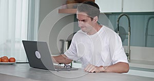Aggressive man, dissatisfied with results of working at laptop, take off glasses and aggressively beats his fist on