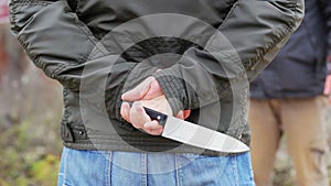 Aggressive man with a knife behind his back