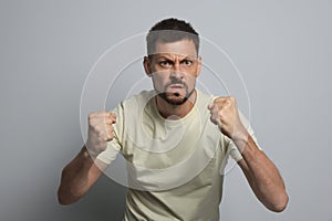 Aggressive man ready to fight on grey background