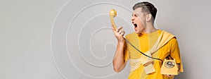 Aggressive man screaming at yellow telephone