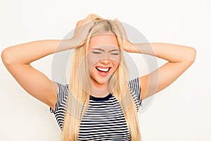 Aggressive sad young woman holding head and screaming