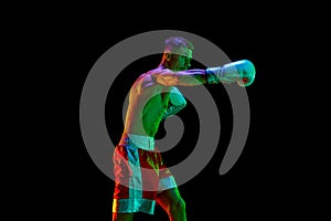 Aggressive shirtless boxer, mixed martial art fighter preparing to fight against black mode background in mixed neon