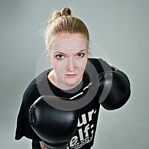 Aggressive teenager girl with box gloves on the grey background