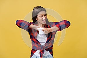 Aggressive young caucasian woman tears contract or white sheet of paper. Isolated over yellow background.