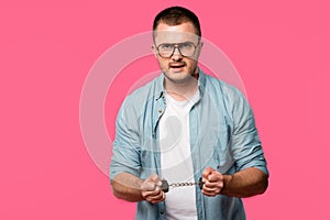 aggressive young man in handcuffs and eyeglasses looking at camera isolated