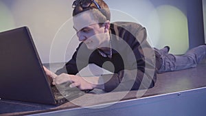 Aggressive young man with a laptop, lying on the floor at nightclub