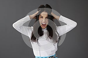 Aggressive young woman screaming and holding head with hands portrait