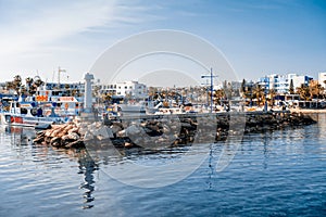 AGIA NAPA, CYPRUS - April 3, 2016: Entrance to the little port with fishing and cruise boats, people resting near the beacon