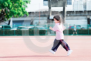 Agile children jogging in exercise stadium. Cute girl wearing white pants and sports shoes.