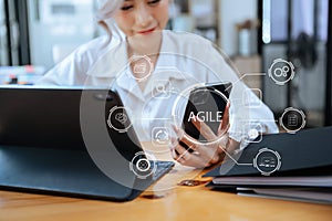 Agile development methodology concept. Business hand using laptop computer and tablet with virtual screen Agile icon on modern