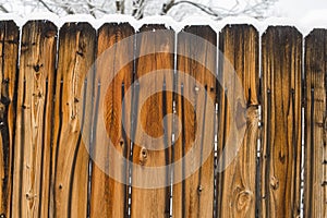 An aging cedar fence after a snow storm