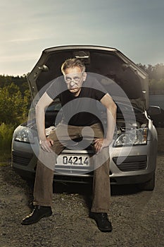 Older man alone on route checking unfunctional engine in late summer light