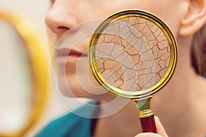 Aging and dry face skin concept - woman with magnifying glass photo