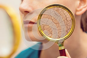 Aging and dry face skin concept - woman with magnifying glass