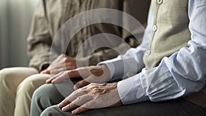 Aging husband and wife sitting together on sofa, support and understanding