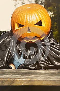 Aging man in city park haunts with pumpkin head