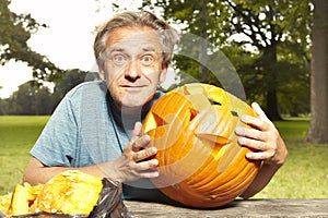 Aging man in city park preparing funny helloween pumpkin